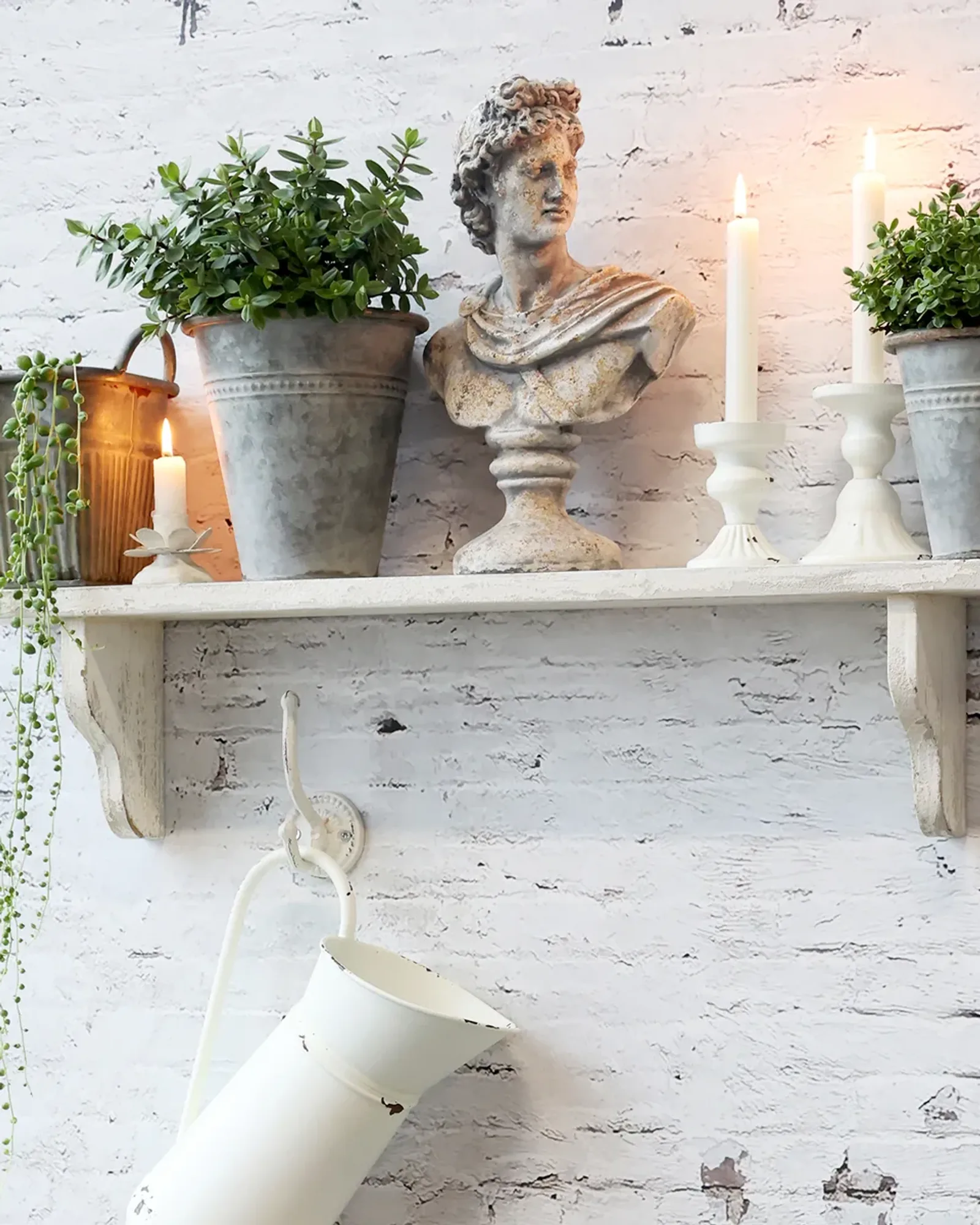 Antique-zinc planters with an embossed band under the rim, in graduated sizes, on a styled shelf with candles and a jug.